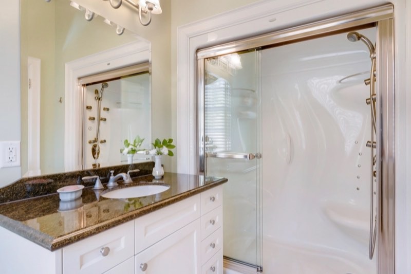 A bathroom with polished glass shower doors and a clear vanity.