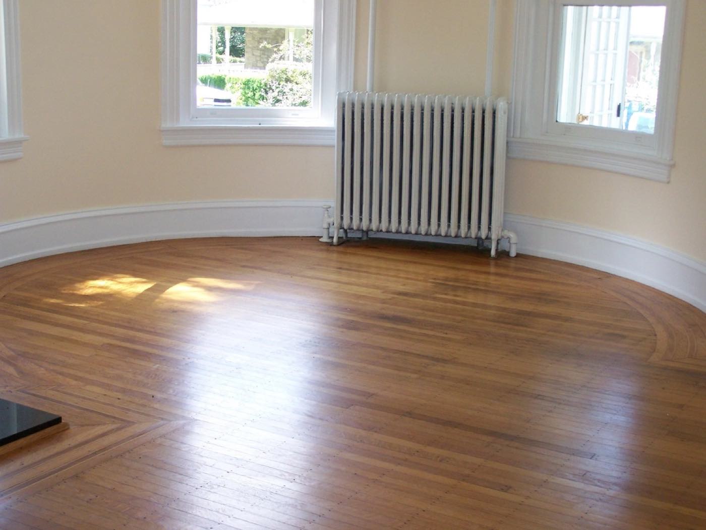 An empty room with bare hardwood floors, clean baseboards and no dust in the corners.
