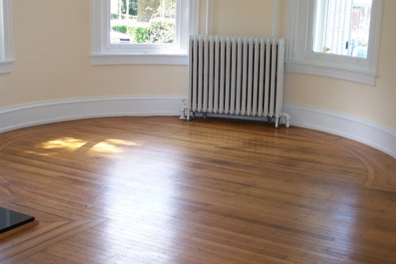 An empty room with bare hardwood floors and clean baseboards.